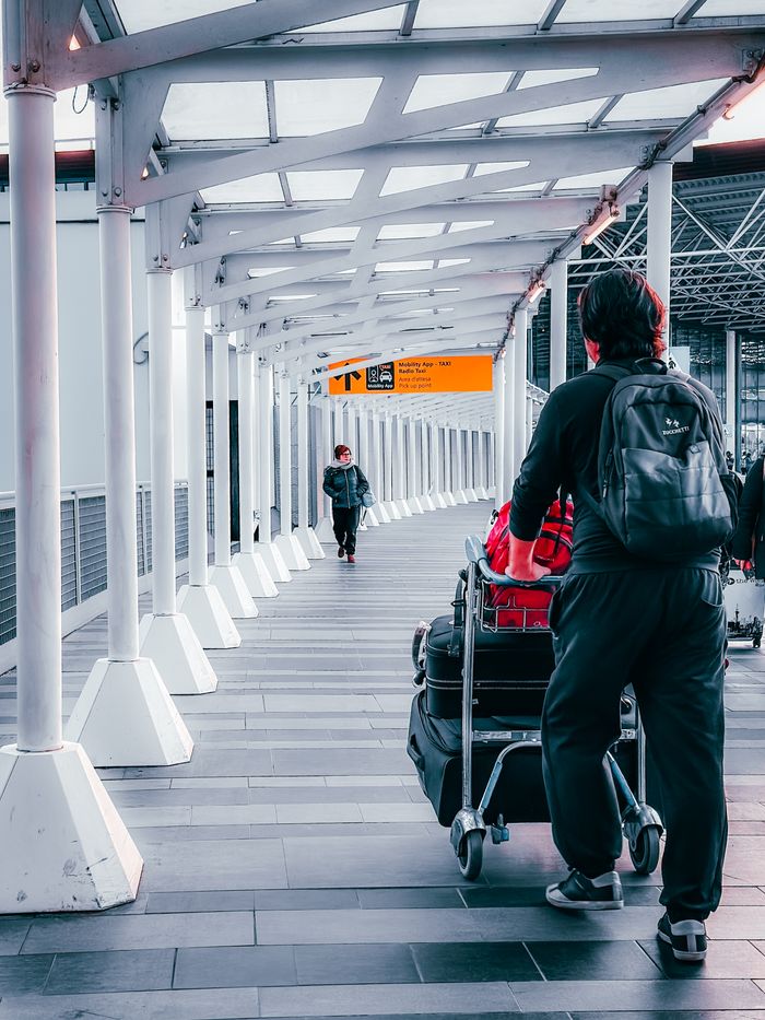 Services Travelers with luggage trolleys navigating through Dortmund Airport's terminal walkway.