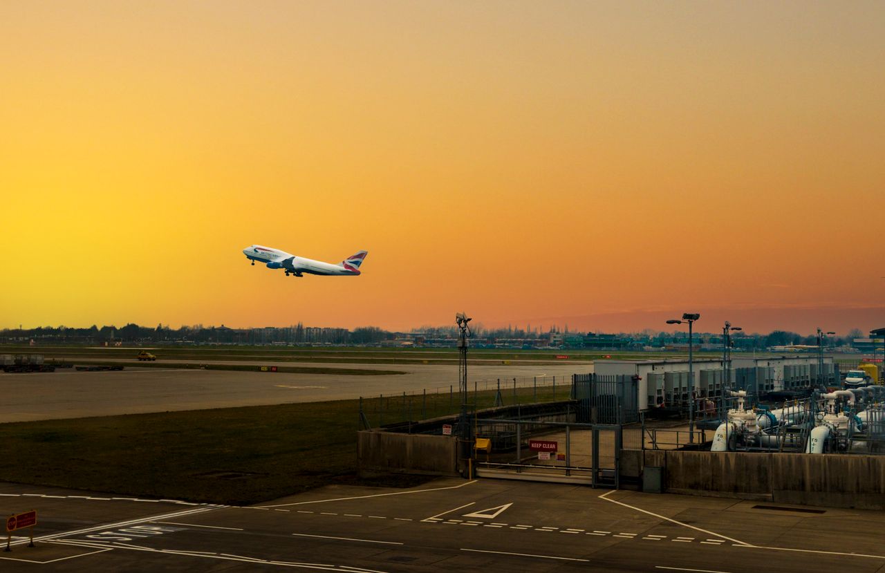 Services Airplane ascending during sunset at Heathrow Airport, capturing the vibrant sky.
